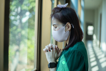 Woman stay at church wearing face mask for protect coronavirus covid-19. Prayer female worship god and praying for coronavirus crisis.