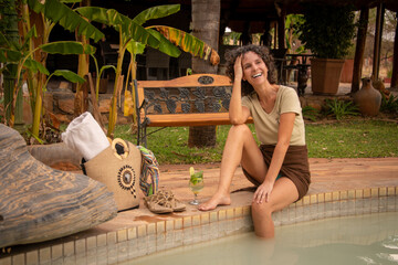 Poster - Laughing brunette sitting by pool with bag