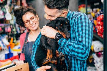 Wall Mural - Happy couple buying toys and food for their Dachshund in pet shop.