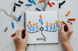 © Татьяна - A girl drawing a celebration card with menorah (traditional candelabra) and candles for Happy Hanukkah jewish holiday.