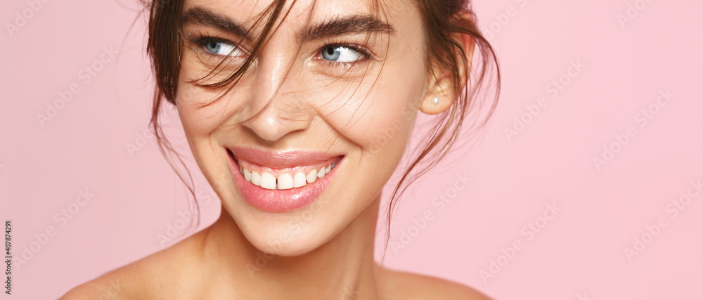 Close-up of fresh natural woman with nude makeup, white smile, looking aside on pink background. Romantic girl with clean hydrated skin, well-nourished smooth face - obrazy, fototapety, plakaty 