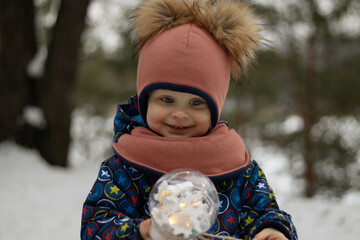 Cute child in winter clothes in the park smiling and holding a sparkler in hand. 