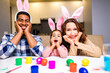 © yurakrasil - mixed race family painting eggs in cozy kitchen