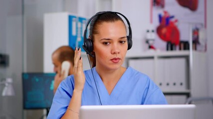 Wall Mural - Doctor assistant using headphones in hospital answering to patients calls for appointments and consultations. Healthcare physician in medicine uniform, doctor nurse helping with telehealth