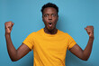© Viktor Koldunov - Happy excited african man screaming and celebrating succcess with two fists up over blue background