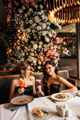 Wall Mural - two beautiful women in elegant dresses posing in luxury restaurant