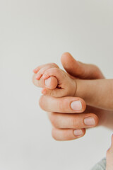 Handle of a newborn close-up in the hands of dad. Newborn baby holds dad's finger in close-up.