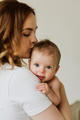 beautiful mom hugs and kisses the newborn in the studio on a white background. a young mother in a w