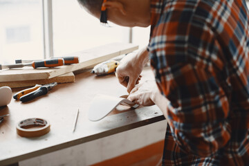 Wall Mural - Craftsman cutting a wooden plank. Worker with wood. Man in a cell shirt.