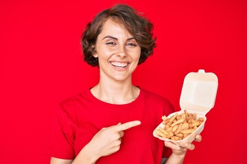 Sticker - Young hispanic woman holding potato chip smiling happy pointing with hand and finger