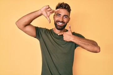 Young hispanic man wearing casual clothes smiling making frame with hands and fingers with happy face. creativity and photography concept.