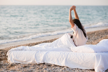 Woman wearing pajamas wake up in bed at beach over nature sea background closeup. Good morning. Summer season. Freedom concept.