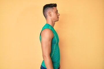 Wall Mural - Young hispanic boy wearing sporty style with sleeveless shirt looking to side, relax profile pose with natural face with confident smile.