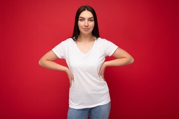 Young beautiful brunette female person with sincere emotions isolated on background wall with copy space wearing casual white t-shirt for mockup. Positive concept