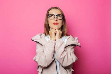 Wall Mural - Pensive young woman in pink jacket, pink isolated background