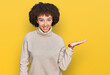© Krakenimages.com - Young hispanic girl wearing wool winter sweater smiling cheerful presenting and pointing with palm of hand looking at the camera.