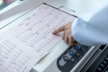 Wall Mural - Doctor holding a cardiogram test. Doctor with electrocardiogram equipment making cardiogram test to patient in clinic.