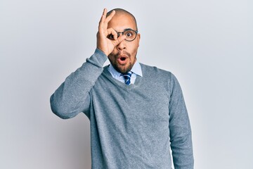 Poster - Hispanic adult man wearing glasses and business style doing ok gesture shocked with surprised face, eye looking through fingers. unbelieving expression.