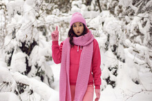 Woman In Pink Clothes A Jacket A Knitted Scarf And A Hat Stands In A Snowy Forest In Winter