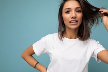 Wall Mural - Attractive beautiful pretty charming fascinating young brunette woman in casual white t-shirt for mockup isolated on blue background with free space