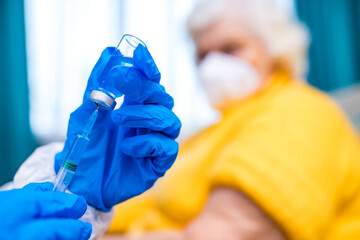 Wall Mural - 80-year-old woman is given the covid-19 vaccine by a doctor in home