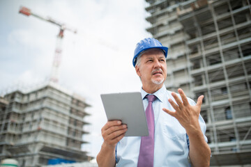 Wall Mural - Site manager using tablet in front of a construction site