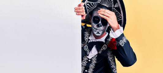 Poster - Young man wearing mexican day of the dead costume holding blank empty banner stressed and frustrated with hand on head, surprised and angry face