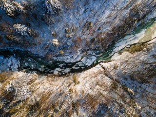 Wall Mural - Frozen River Flowing Trough Forest. Bieszczady Mountains Park in Poland. Drone View. Winter Season