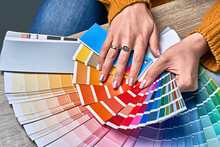 Color Wheel For Choosing Paint Tone. Hands Of Female Interior Designer Working With Palette For Choosing Colors. Creative Process Concept. Comparing Options With Matching Hues.