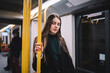 © GalakticDreamer - Cheerful young woman in warm casual wear inside subway train