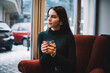 © GalakticDreamer - Attractive young woman sitting on armchair in cafe with glass of water
