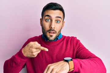 Sticker - Young hispanic man wearing casual clothes in hurry pointing to watch time, impatience, upset and angry for deadline delay