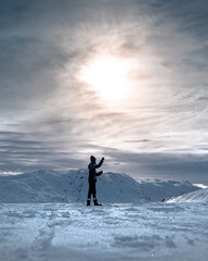 Poster - Vertical shot of a person fishing on a frozen lake under the cloudy sky