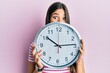 © Krakenimages.com - Young brunette woman holding big clock covering face celebrating crazy and amazed for success with open eyes screaming excited.