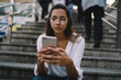 © GalakticDreamer - Focused woman using cellphone while sitting on stairs