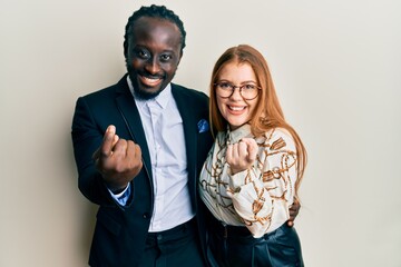 Canvas Print - Young interracial couple wearing business and elegant clothes beckoning come here gesture with hand inviting welcoming happy and smiling