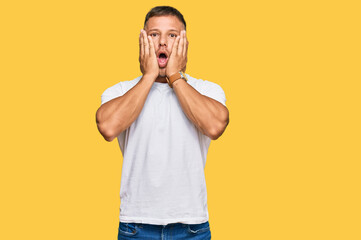 Poster - Handsome muscle man wearing casual white tshirt afraid and shocked, surprise and amazed expression with hands on face