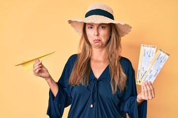 Canvas Print - Middle age hispanic woman wearing summer hat holding boarding pass and paper airplane depressed and worry for distress, crying angry and afraid. sad expression.