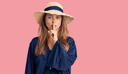 Poster - Middle age hispanic woman wearing summer hat asking to be quiet with finger on lips. silence and secret concept.