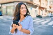 © Krakenimages.com - Young hispanic businesswoman smiling happy using smartphone at the city.