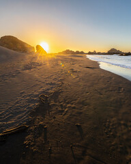 Wall Mural - an awe sunset in an idyllic beach landscape with the sunset over the water and the sunlight generati