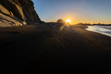 Wall Mural - an awe sunset in an idyllic beach landscape with the sunset over the water and the sunlight generati