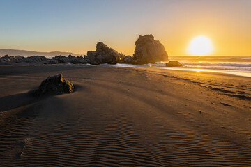 Wall Mural - an awe sunset in an idyllic beach landscape with the sunset over the water and the sunlight generati