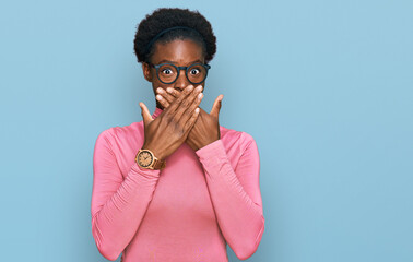 Wall Mural - Young african american girl wearing casual clothes and glasses shocked covering mouth with hands for mistake. secret concept.