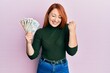 © Krakenimages.com - Beautiful redhead woman holding united kingdom pounds screaming proud, celebrating victory and success very excited with raised arm