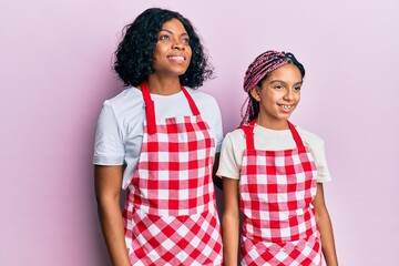 Sticker - Beautiful african american mother and daughter wearing baker uniform looking to side, relax profile pose with natural face and confident smile.