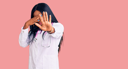 Sticker - Young african american woman wearing doctor stethoscope covering eyes with hands and doing stop gesture with sad and fear expression. embarrassed and negative concept.