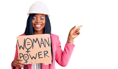 Poster - Young african american woman wearing architect helmet holding woman power banner smiling happy pointing with hand and finger to the side