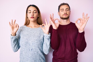 Poster - Beautiful couple wearing casual clothes relax and smiling with eyes closed doing meditation gesture with fingers. yoga concept.