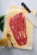 © fahrwasser - Raw flank steak on a cutting board with a meat cleaver ready to be marinated